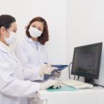 Professional Asian women in dental clinic discussing panoramic x-ray on screen of computer in office
